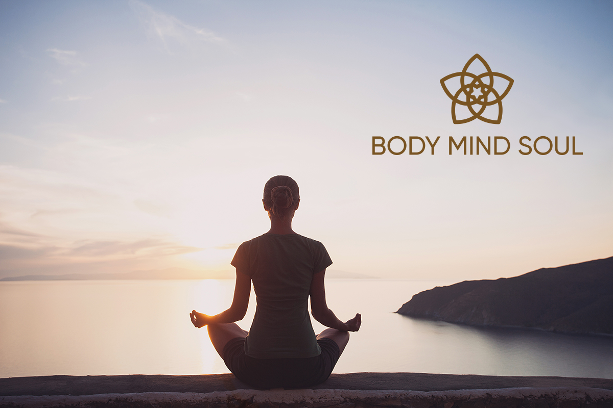 Frau sitzend im Yoga Schneidersitz, bei Sonnenaufgang am Meer, in Meditation und Achtsamkeit, trägt Haarschmuck Body Mind Soul von Trisa Accessoires