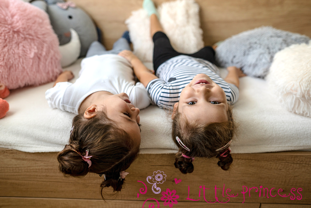 zwei Mädchen mit neckischen Frisuren, liegen auf dem Bett, tragen Haarschmuck von Little Princess von Trisa Accessoires.